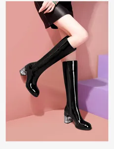 Side view of stylish black patent leather knee-high boots featuring unique glitter chunky heels.