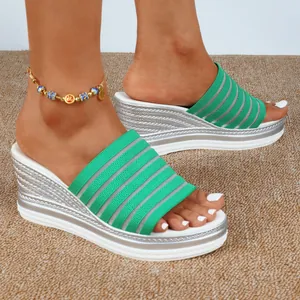 Nahaufnahme von Damen-Keilsandalen in Grün und Silber mit gestreiftem Strickobermaterial.