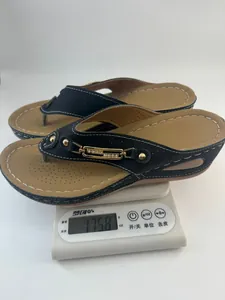 Détail d'une paire de tongs compensées noires légères pesant 175,8 g sur une balance numérique
