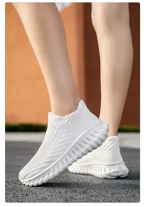 Detailed view of breathable white fly-knit slip-on sneakers for men and women on pavement