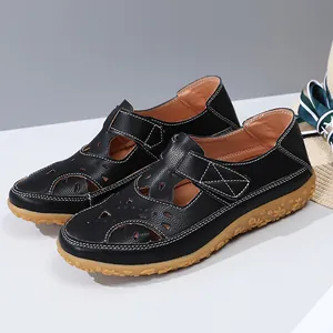 Detailed macro view of black laser-cut flat sandals with floral patterned rubber soles