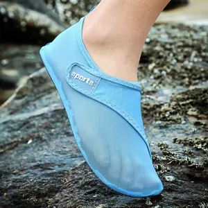 Macro view of blue breathable mesh water shoes worn on a natural rocky beach background