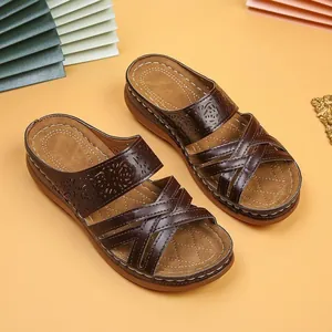 Close-up of brown women's wedge sandals with laser-cut detailing and criss-cross straps.