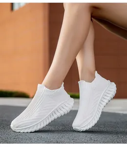 Close-up view of lightweight white breathable flyknit slip-on sneakers on model feet