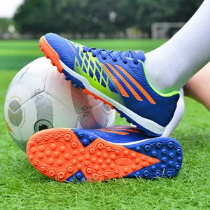 Duurzame blauw-oranje voetbalschoenen voor jongeren en volwassenen op een grasveld