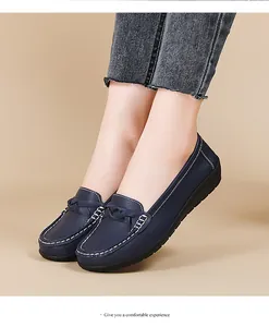 Detailed view of dark blue women's flat loafers featuring white contrast stitching on model