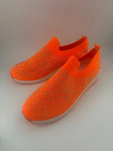 Primer plano de zapatillas de punto naranja vibrante con detalles de diamantes de imitación