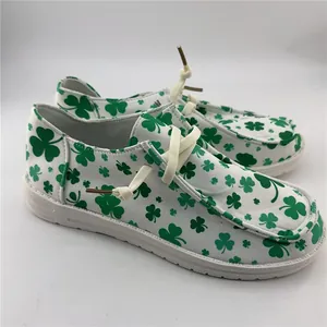 Detailed side view of women's white canvas loafers with green shamrock clover pattern print
