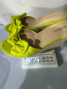 Macro view of lime green bow wedge sandals weighing 585 grams on a scale