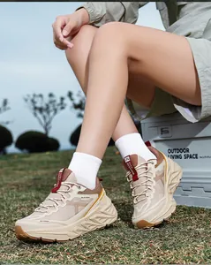 Close-up view of stylish beige outdoor running shoes with thick soles worn in a field