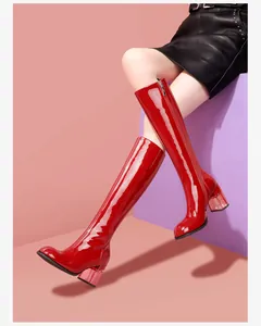 Close-up detail of red patent leather knee-high boots with transparent block heels