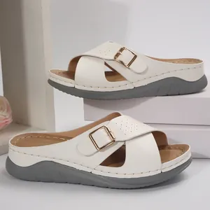 Detail view of white platform sandals with criss-cross straps and gold buckle.