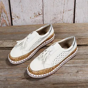 Détail de mocassins blancs à glands et motifs ajourés sur fond en bois rustique