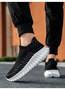Close-up detail of breathable black fly-knit sock sneakers with thick white wavy soles.