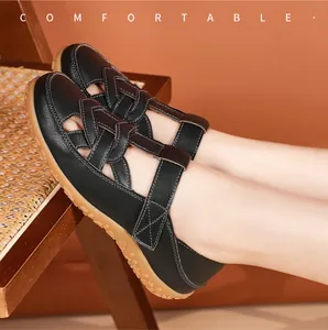 Side view of comfortable black leather hollow-out flat sandals on a foot.