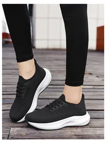Women's breathable fly-knit running sneakers with thick white soles on wooden deck.