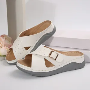 Detail shot of white wedge sandals featuring cross straps and elegant gold buckle