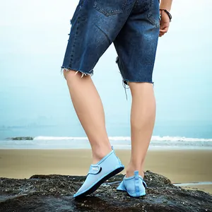 Light blue breathable quick-dry beach shoes worn by a man standing on rocks at the seaside