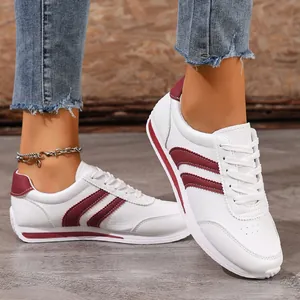 Side view of white women's sneakers with maroon stripes and non-slip soft soles