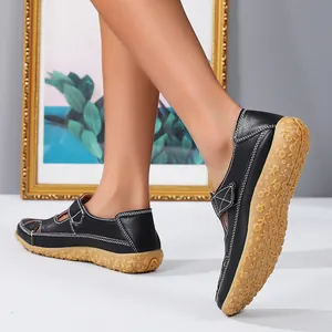 Close-up detail of black hollow-out leather flat sandals with floral patterned sole