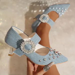 Nahaufnahme von blauen Denim-Pumps mit Kristall-Schnalle und silbernen Nieten