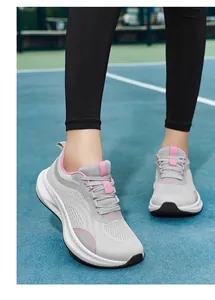 Detailed view of women's breathable fly-knit mesh running shoes with pink accents on a court