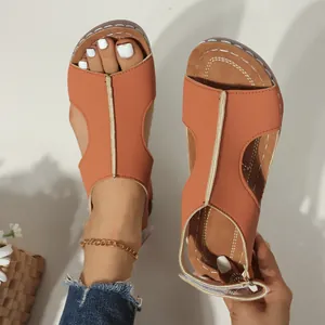 Detailweergave van oranje sleehaksandalen met klittenbandsluiting en decoratief stiksel.