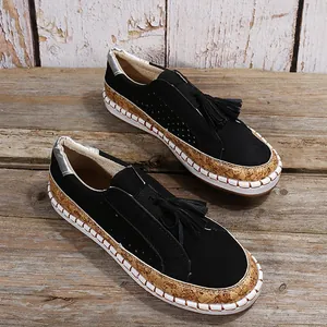 Détail de mocassins noirs à glands avec semelle en liège et motifs découpés.