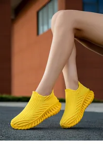 Detailed view of yellow breathable fly-knit slip-on sneakers with wavy thick soles