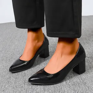 Elegant black patent leather pointed toe chunky heel pumps on-foot detail view.