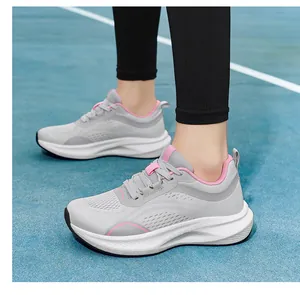 Close-up detail of women's grey and pink breathable mesh running shoes on court.