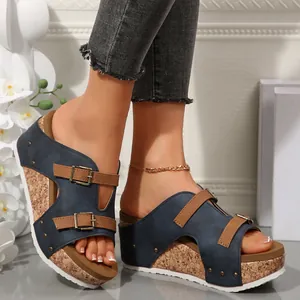 Close-up view of navy blue wedge sandals featuring cork platform and decorative buckle details