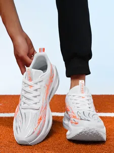 White children's running shoes with orange flame patterns on a track