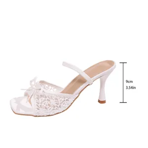 Detail of elegant white lace high-heeled mule with bow and 9cm kitten heel height.