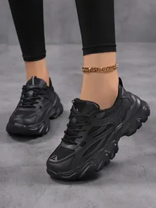 Gros plan de baskets compensées noires élégantes pour femmes portées sur fond gris