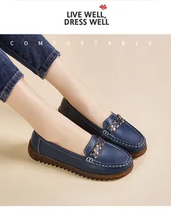 Dettaglio mocassini in pelle blu navy con catena dorata e cuciture bianche.