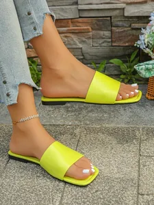 Eleganti ciabatte piatte giallo neon indossate ai piedi con un raffinato sfondo esterno