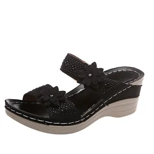 Detailed view of black wedge sandal strap with decorative flowers and shiny rhinestones