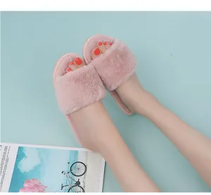 Close-up of pink faux fur open-toe slippers worn on feet in a cozy indoor setting