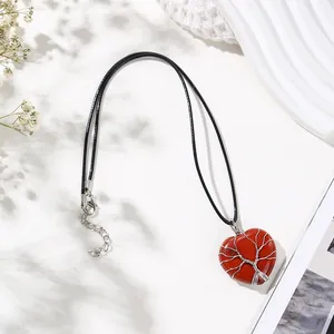 A detailed view of the red stone heart pendant with silver wire wrapped tree of life motif