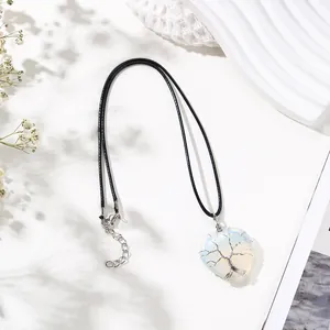 Close-up of white heart crystal pendant with silver tree of life wire wrapping