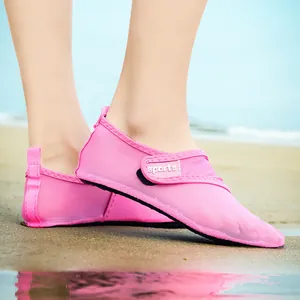 Close-up of pink breathable mesh water shoes with sports Velcro strap on a sunny beach
