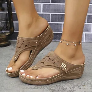 Primer plano de sandalias de cuña marrón con parte superior cortada con láser.