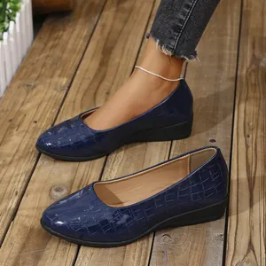 Close-up of elegant navy blue women's wedge shoes featuring embossed crocodile leather texture