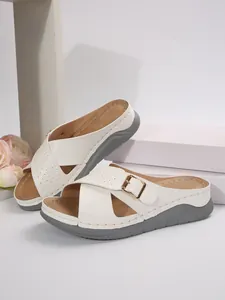 Macro detail view of white platform cross-strap slippers with elegant gold buckle