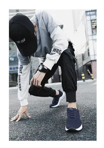 Close-up of navy blue flyknit elevated sneakers worn by a male model on a street background