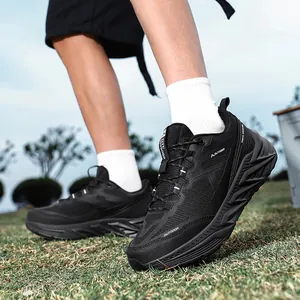 Black outdoor trail running shoes for men with thick geometric cushioned soles on grass