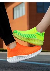 Close-up detail of vibrant neon green and orange fly-knit slip-on walking sneakers for couples.