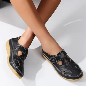Detailed view of black hollow-out flat sandals featuring a hook-and-loop strap.