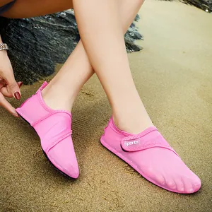 Detailed view of pink mesh water shoes worn on a sandy beach for outdoor swimming.